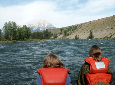 two children looking at the grand tetons on a scenic float down the snake river